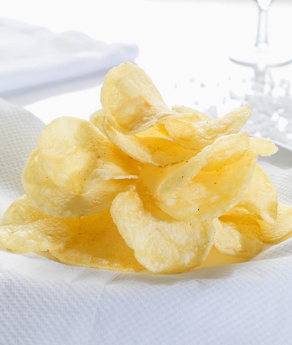 A heap of potato crisps, salt in background