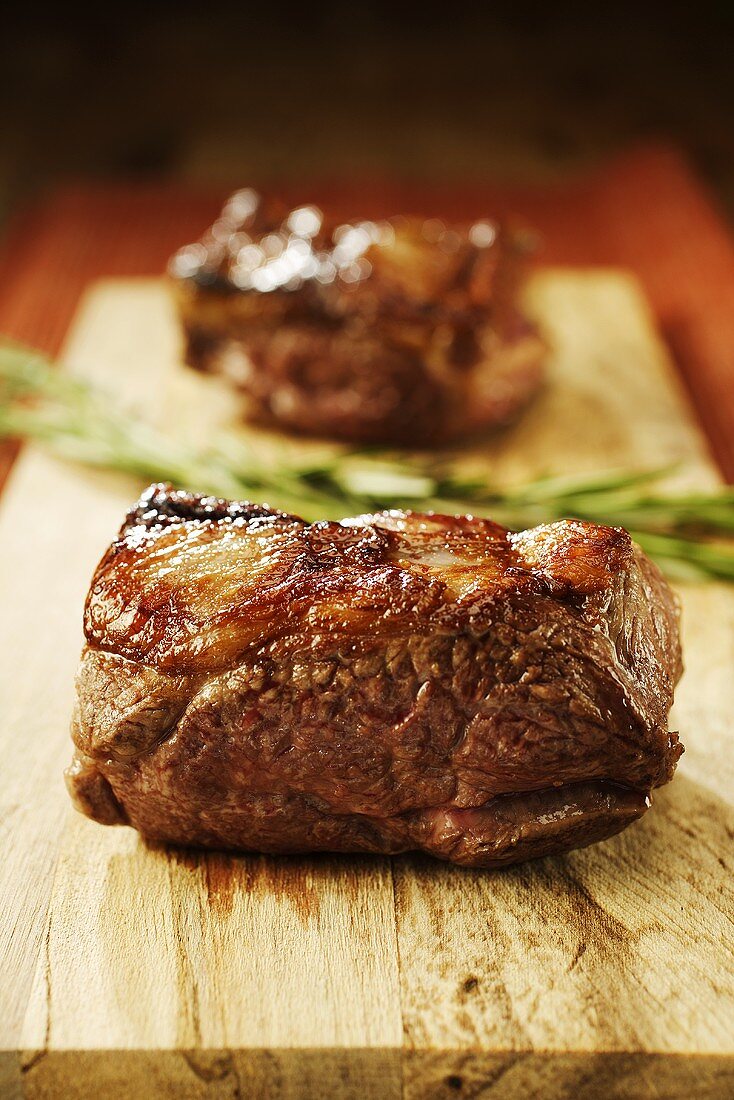 Fried lamb steaks on chopping board