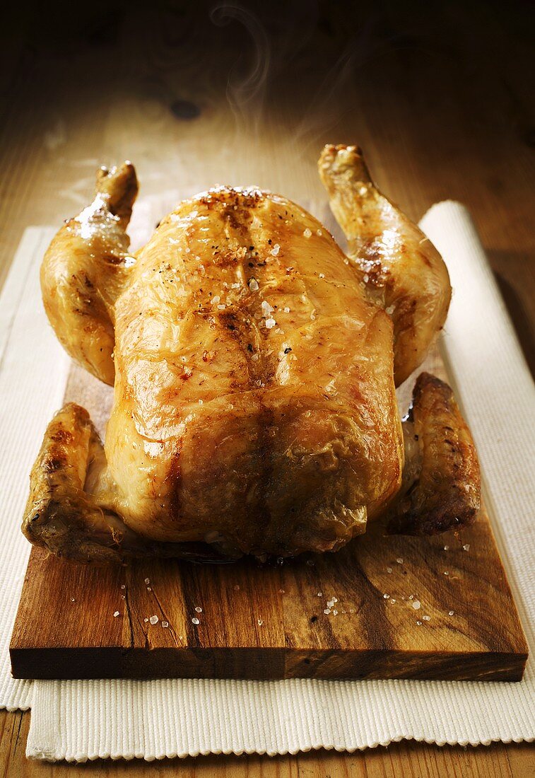 Whole roast chicken on chopping board