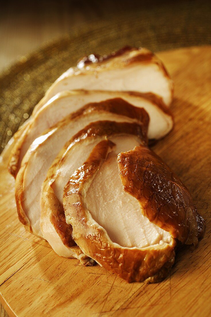 Sliced smoked chicken breast on chopping board