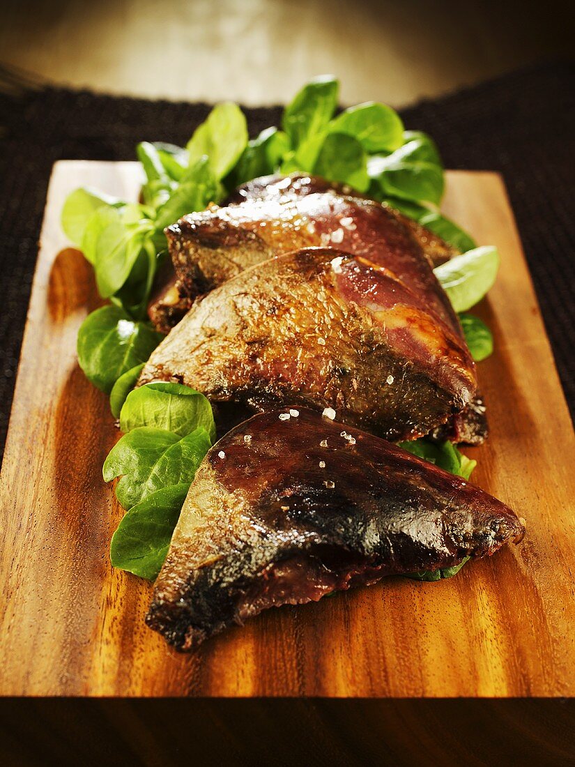 Roast pigeon breasts on chopping board