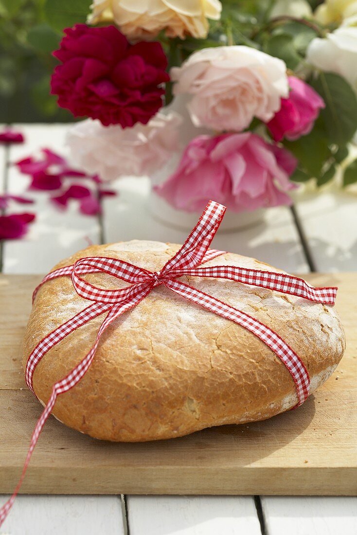 Rustikales Weißbrot mit karierter Schleife auf Gartentisch