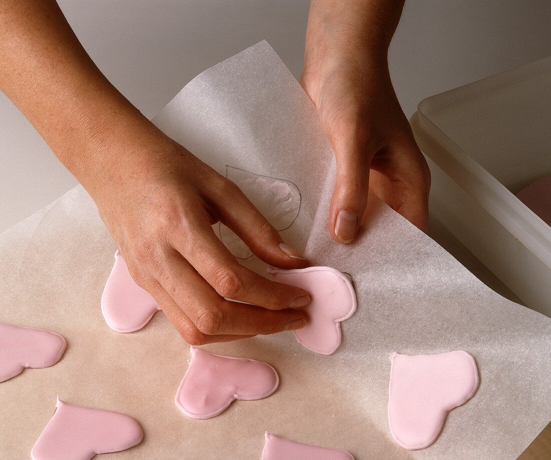 Heart-shaped biscuits being removed from baking paper