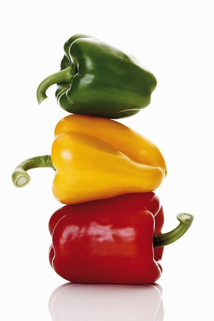 One red, one yellow and one green pepper, stacked