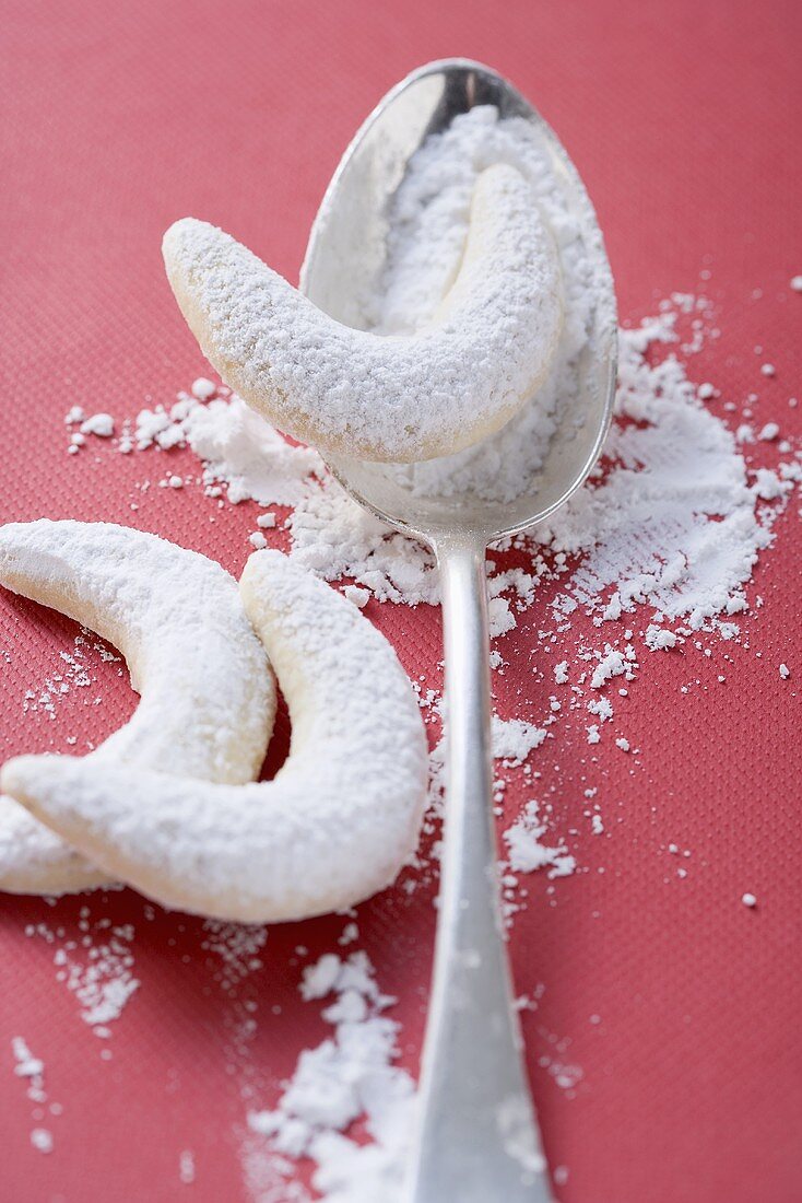 Vanilla crescents with icing sugar, one on spoon