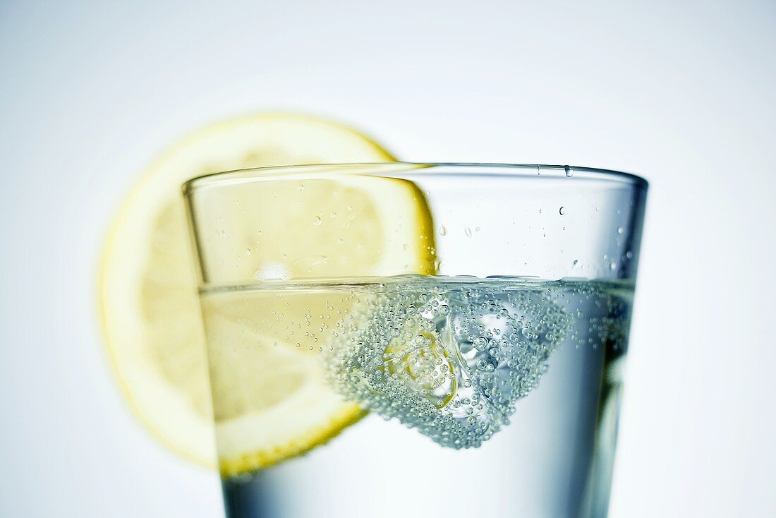 Ice cube and slice of lemon in a glass of water
