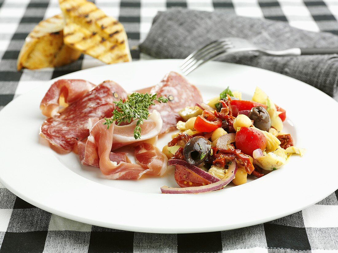 Plate of appetisers: sausage, ham and vegetable salad