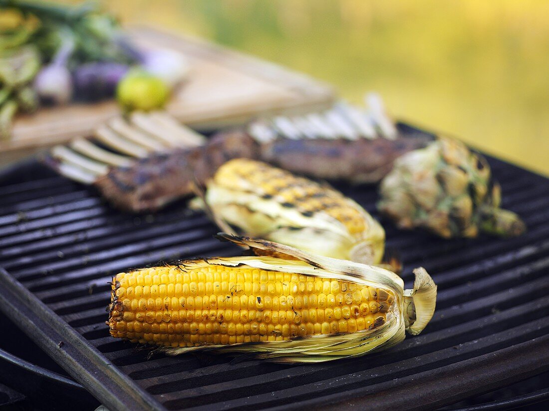 Corn on the cob, lamb chops and artichoke on a barbecue