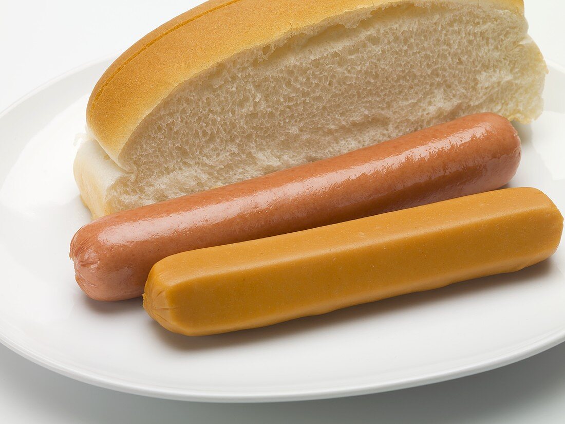 Two typical hot dog sausages and a halved roll