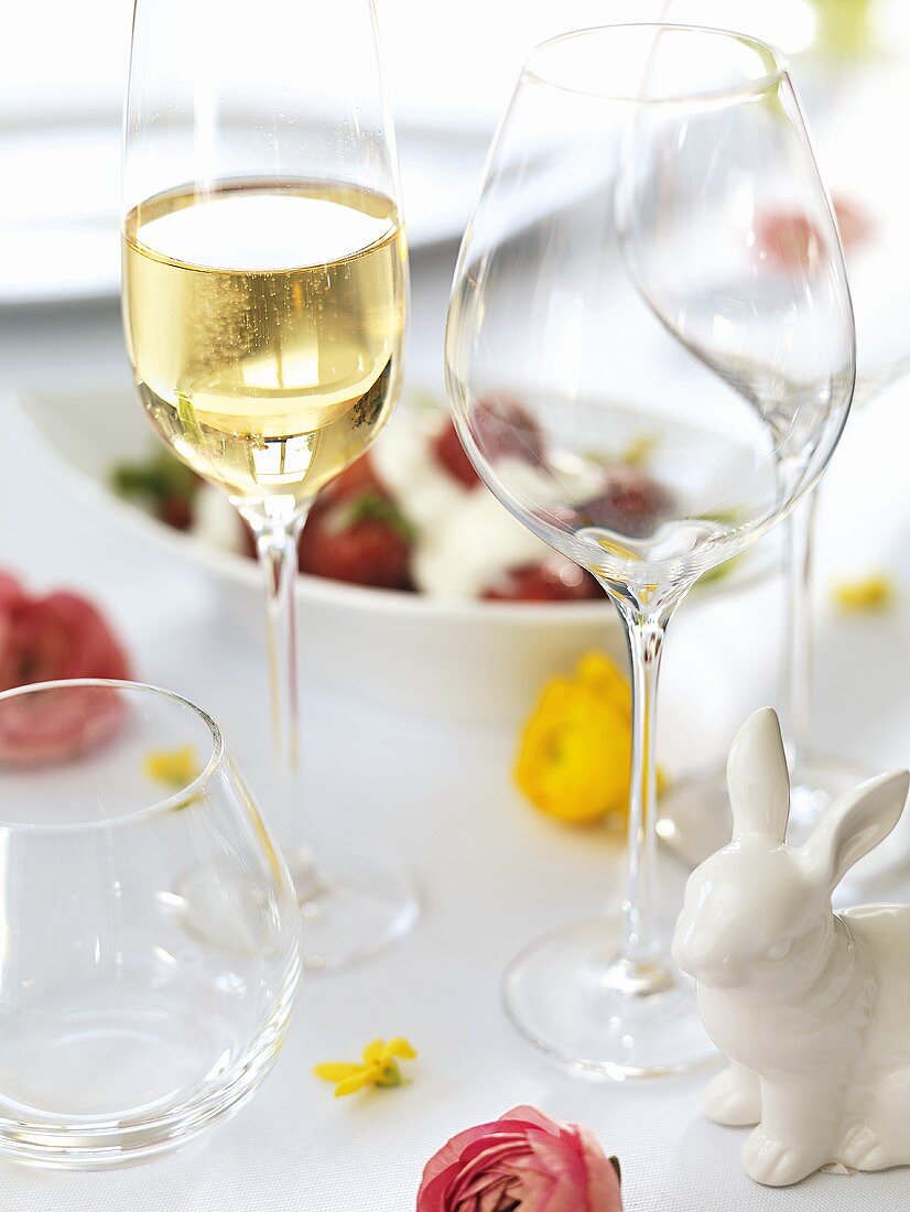 Glass of sparkling wine & empty wine glasses on Easter table