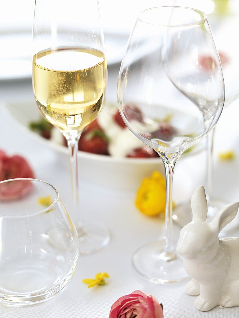 Sektglas und leere Weingläser auf einem Ostertisch