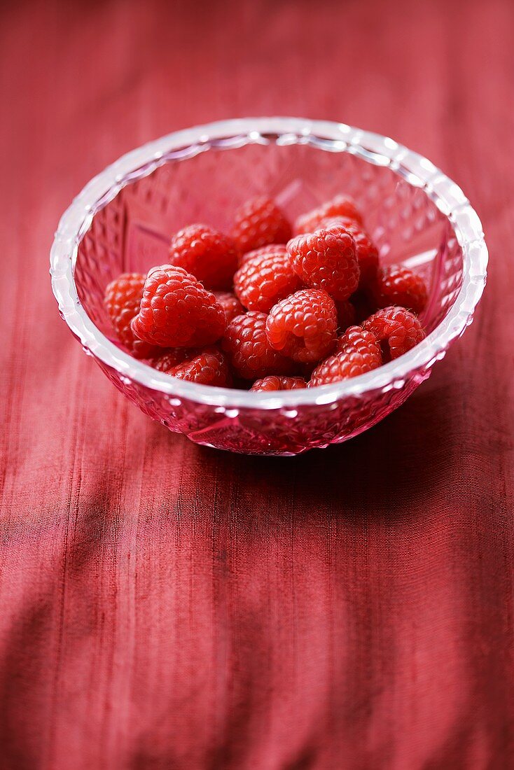 Several raspberries in a crystal bowl