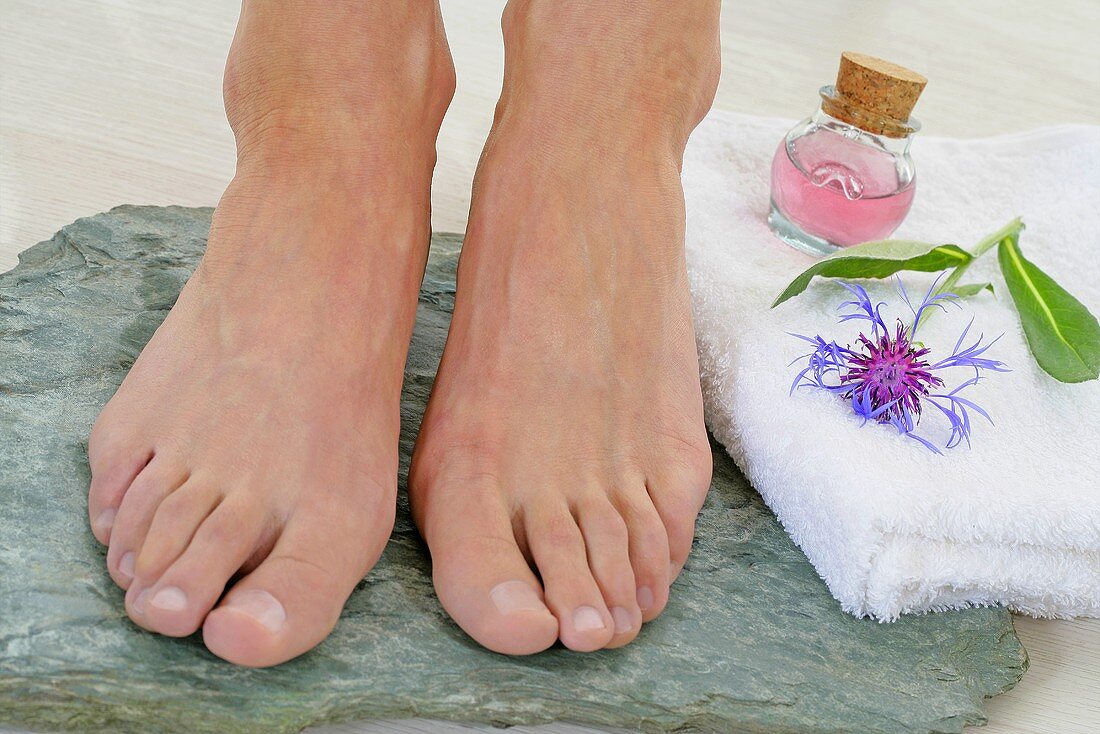 Someone's feet on a stone, towel, cosmetic bottle