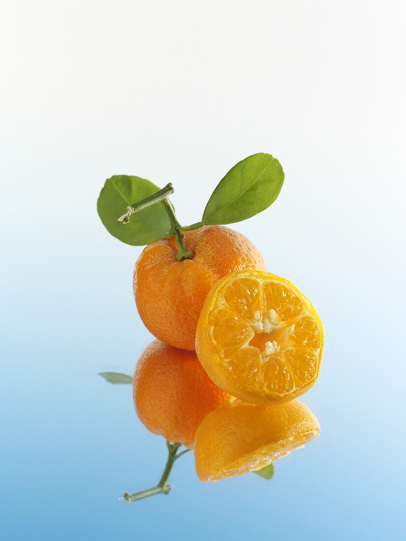 Whole and half mandarin orange with reflection