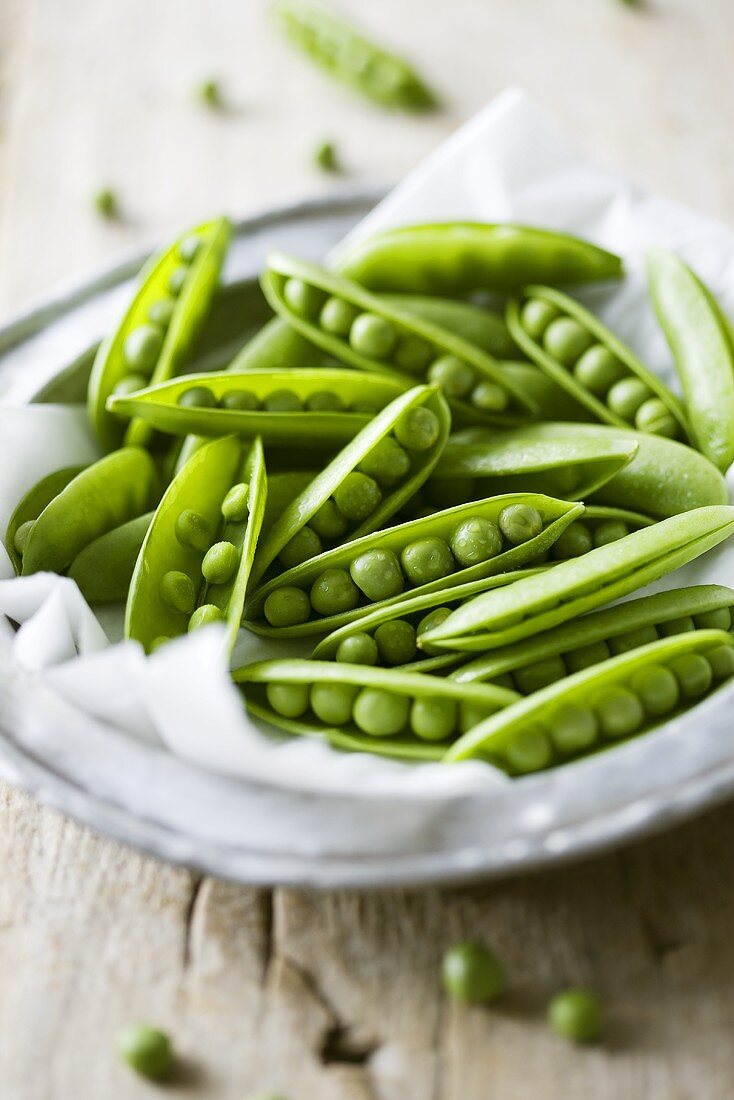 Fresh pea pods on pewter plate