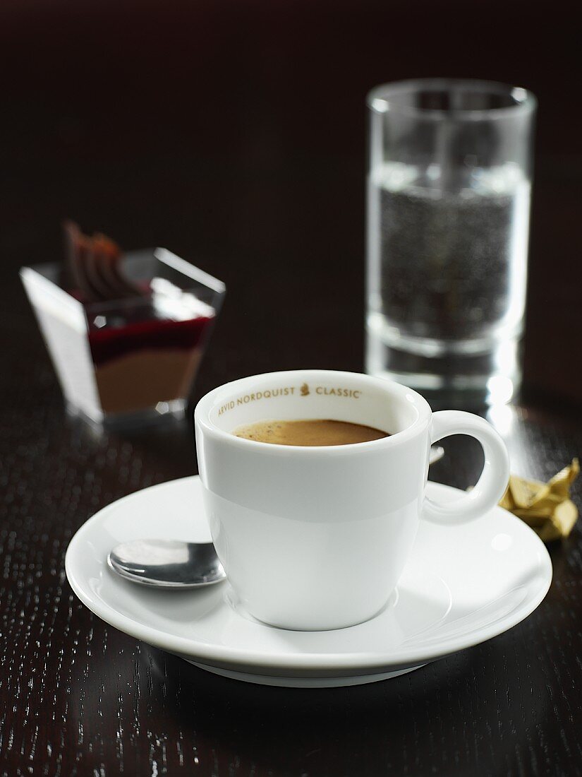 Eine Tasse Espresso mit einem Glas Wasser