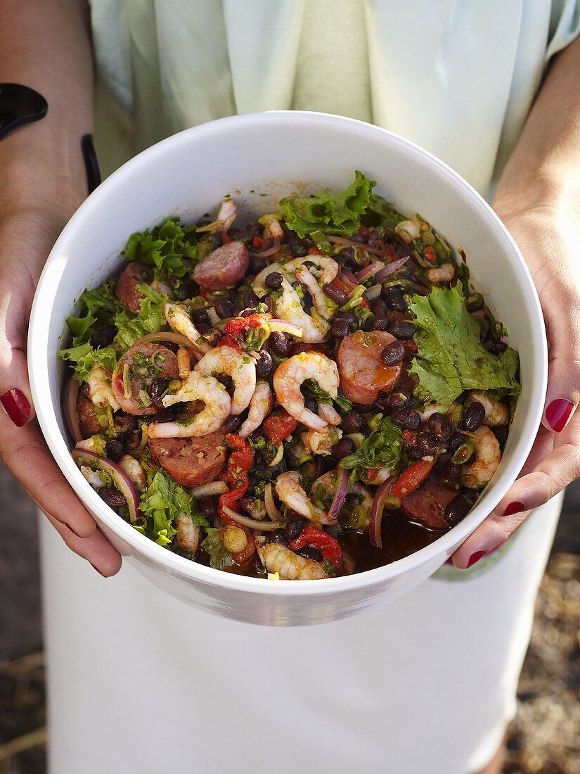 Frauenhände halten Bohnensalat mit Shrimps