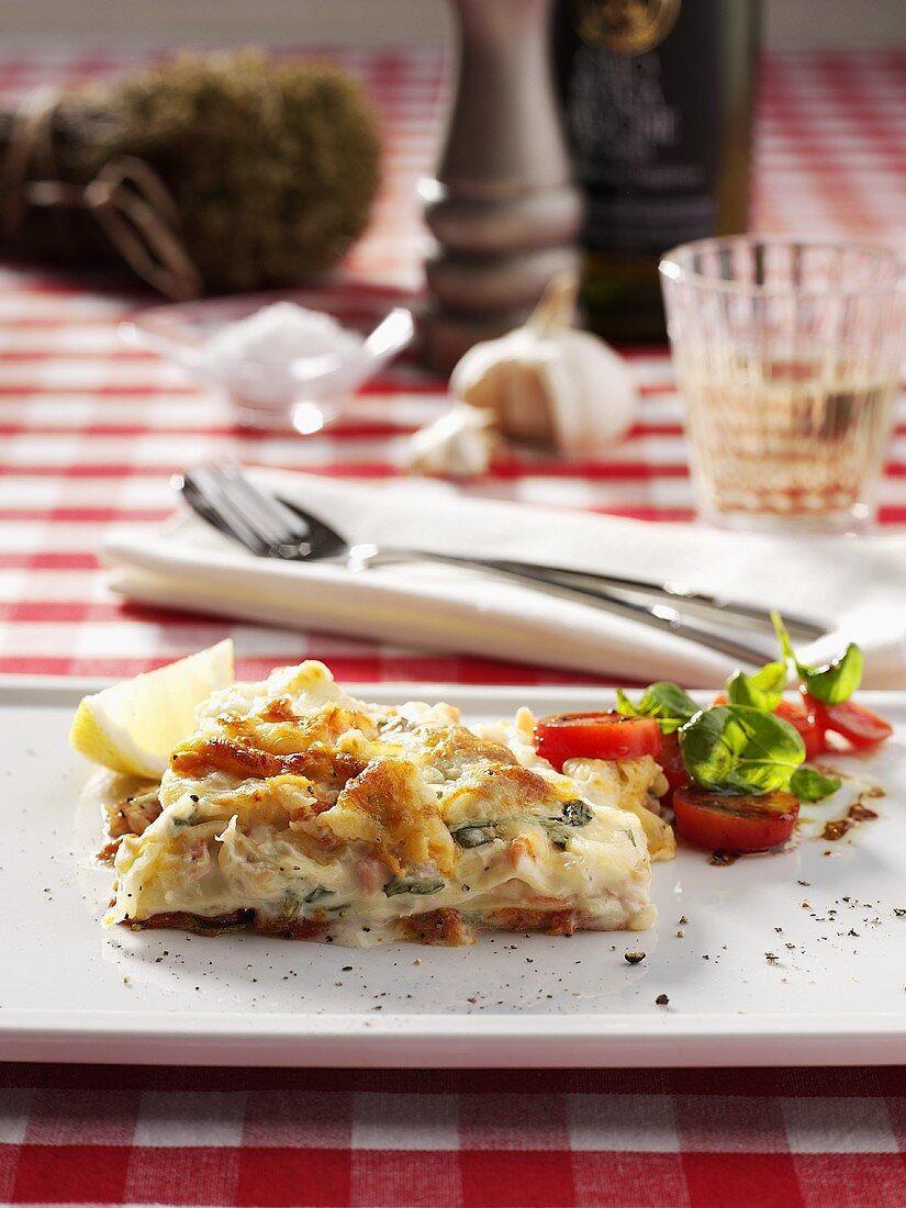 Piece of salmon lasagne garnished with tomato and basil