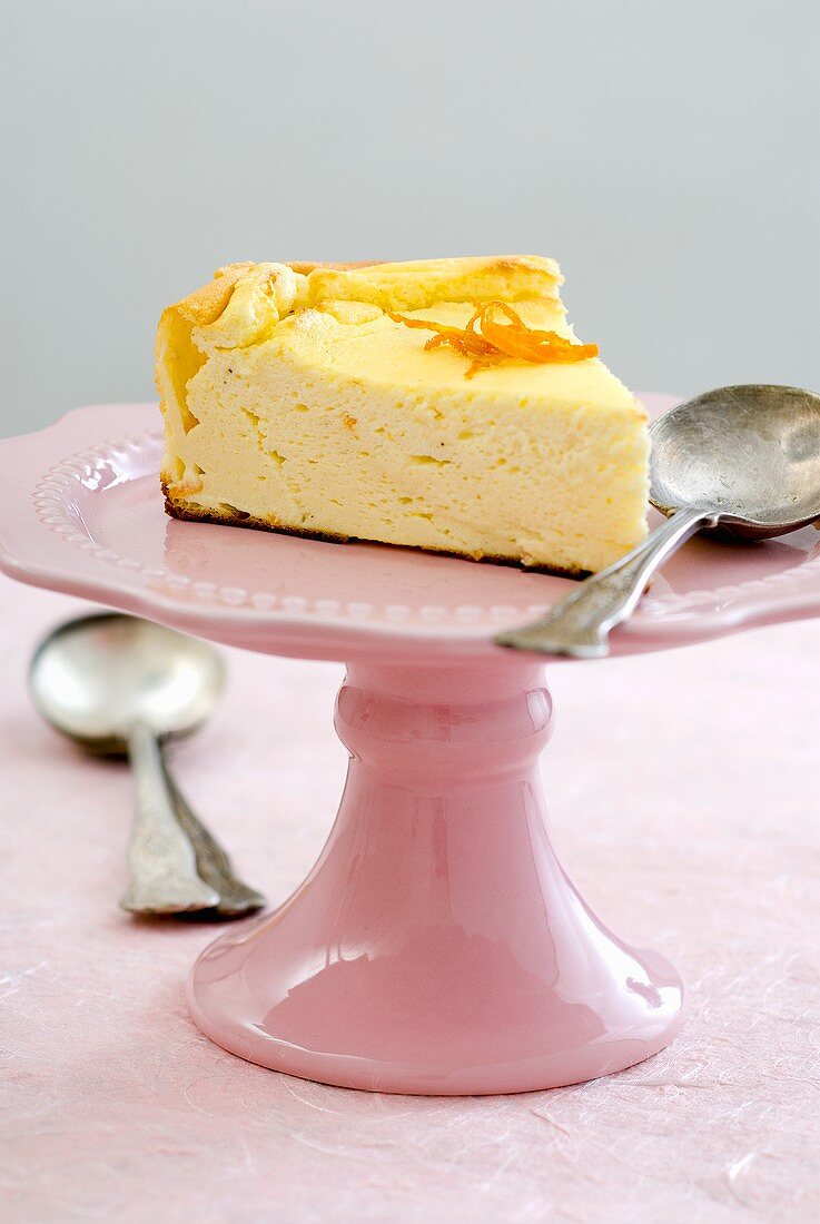 Piece of cheesecake with orange zest on cake stand