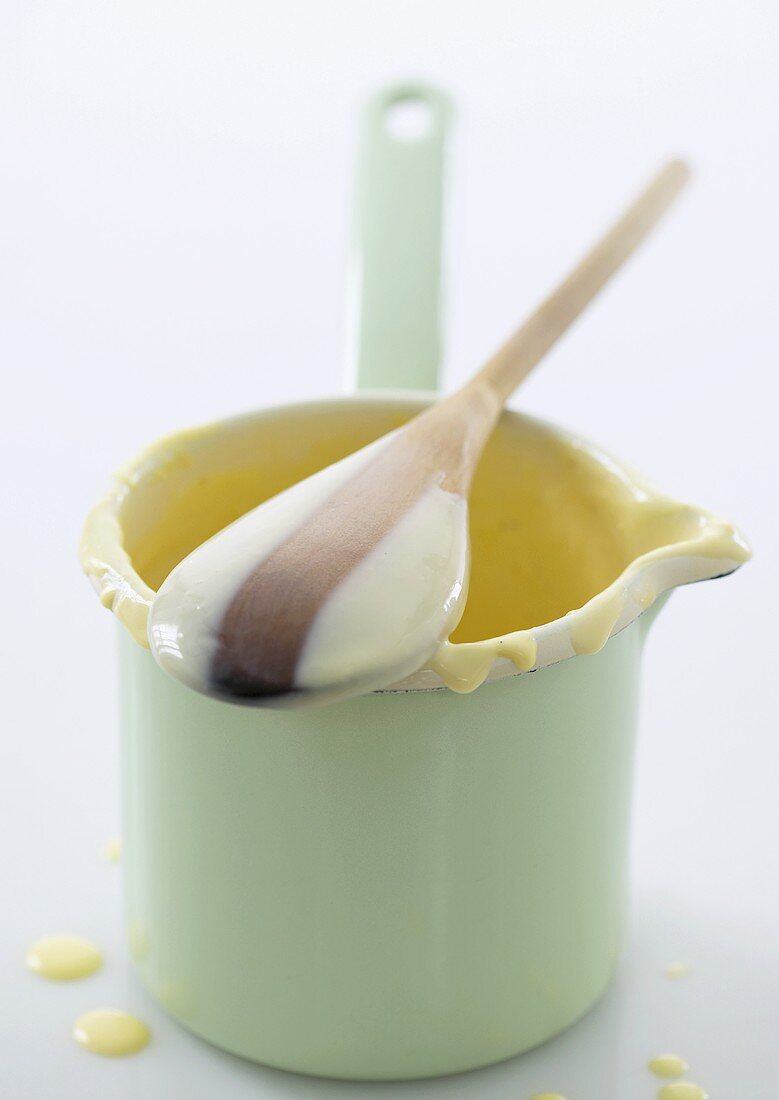 Remains of custard in small jug and on wooden spoon