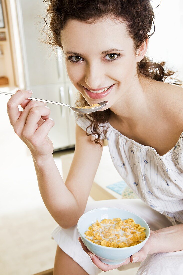 Young woman eating cornflakes with milk