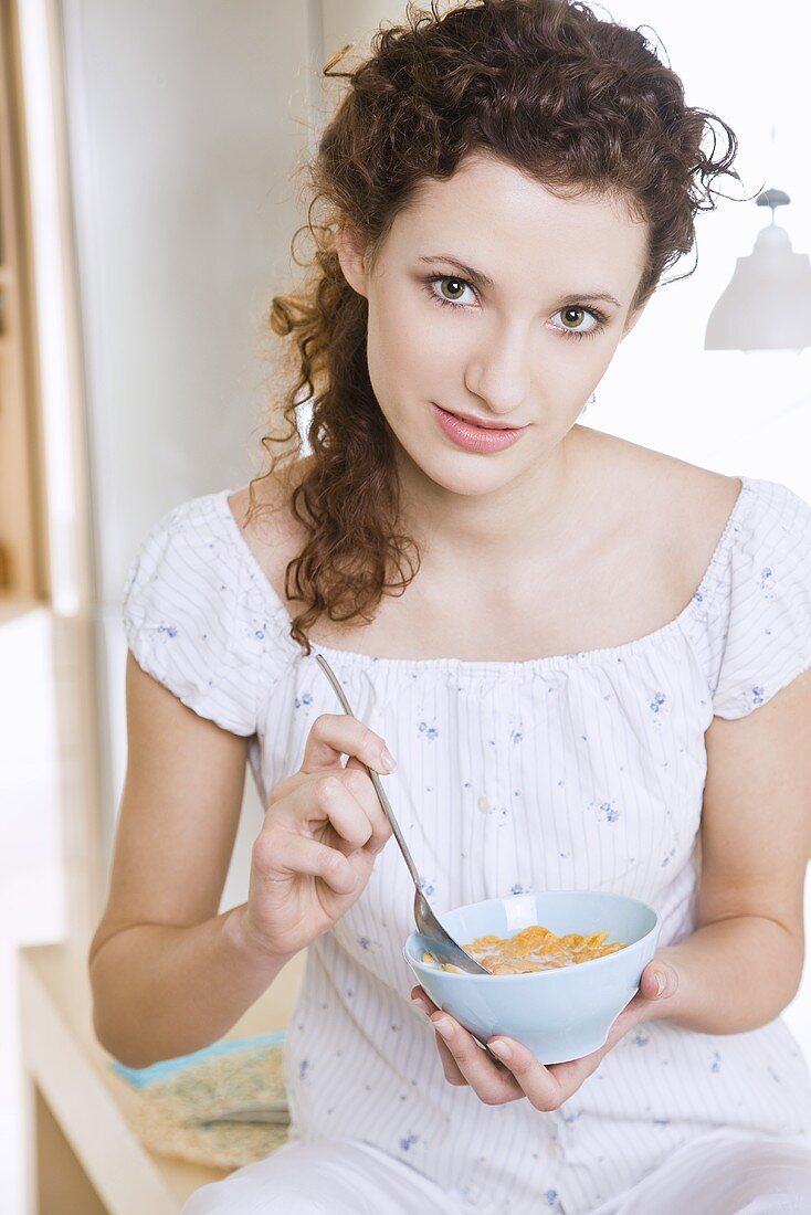 Young woman eating cornflakes with milk