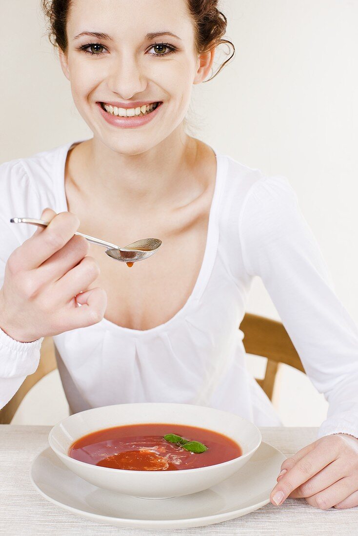 Young woman eating cream of tomato soup