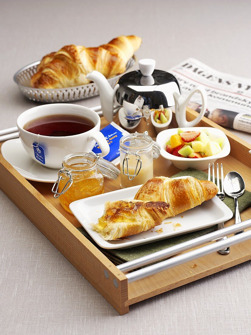 Frühstück mit Tee, Obstsalat und Croissants
