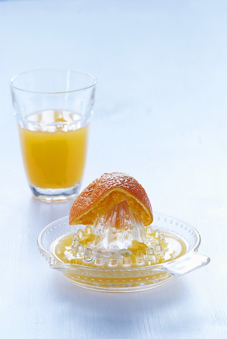 Orange half on citrus squeezer, freshly squeezed orange juice