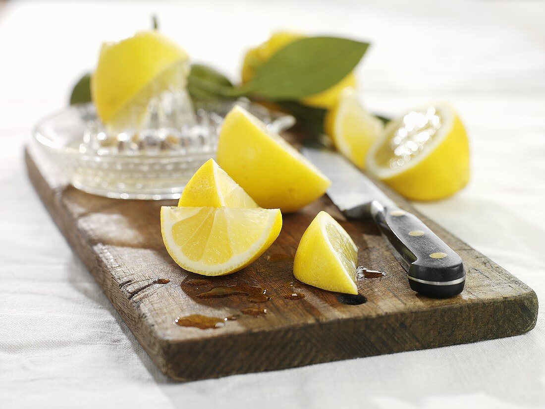 Pieces of lemon with squeezer on wooden board