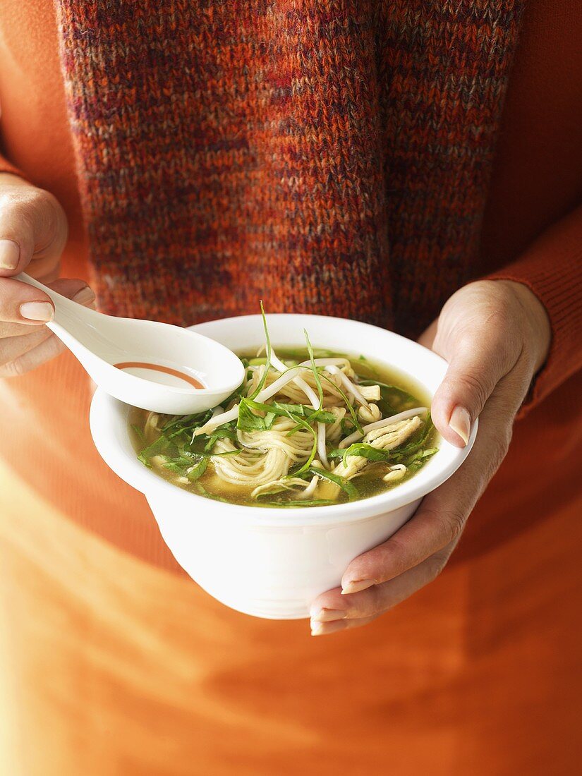 Frau hält Nudelsuppe mit Hähnchen