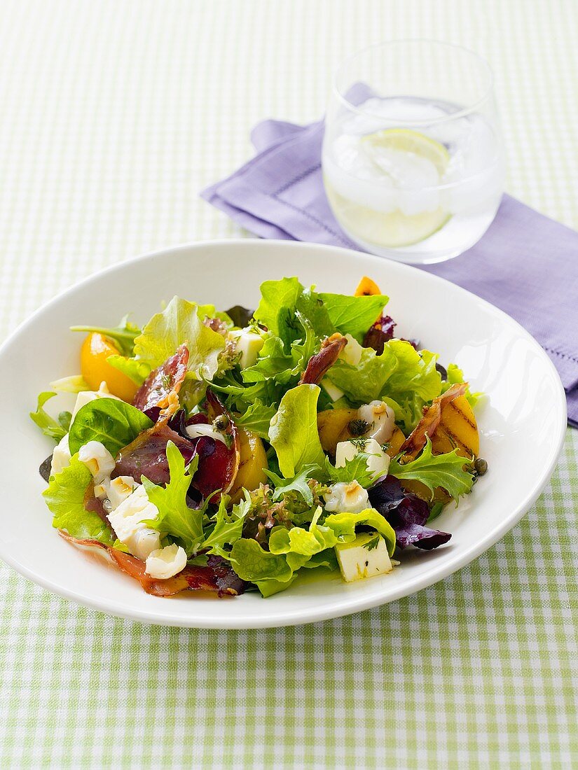Salad leaves with peach wedges, ham and feta