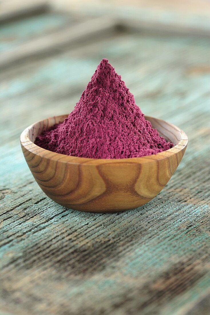 Acai powder (diet aid) in small wooden bowl