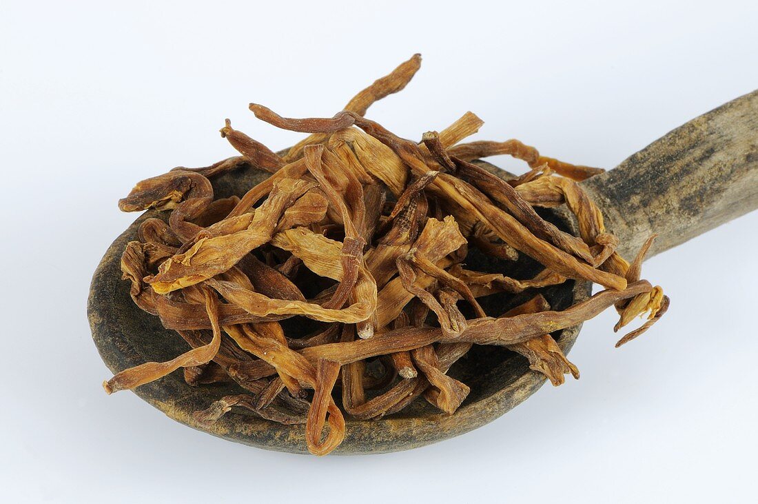 Dried lily buds on wooden spoon