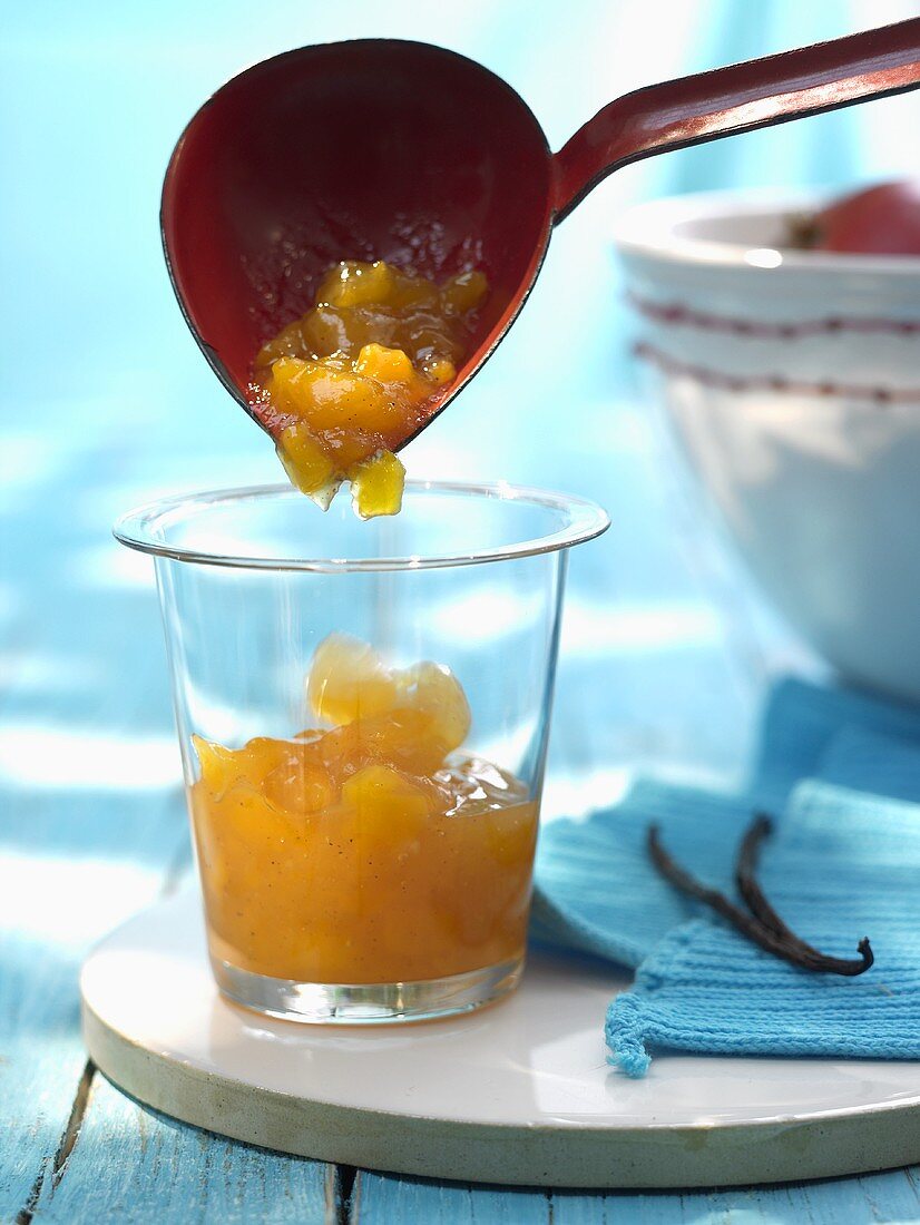 Ladling peach and mango jam into jar
