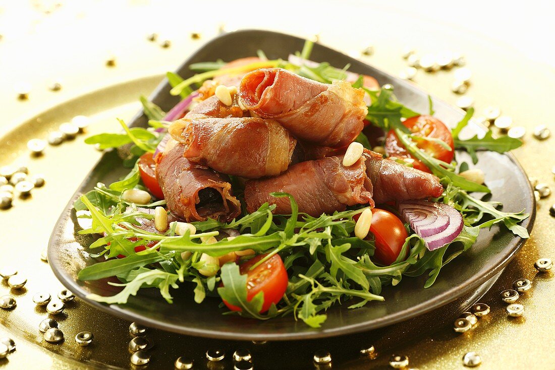 Bacon-wrapped prunes with rocket, tomatoes and pine nuts