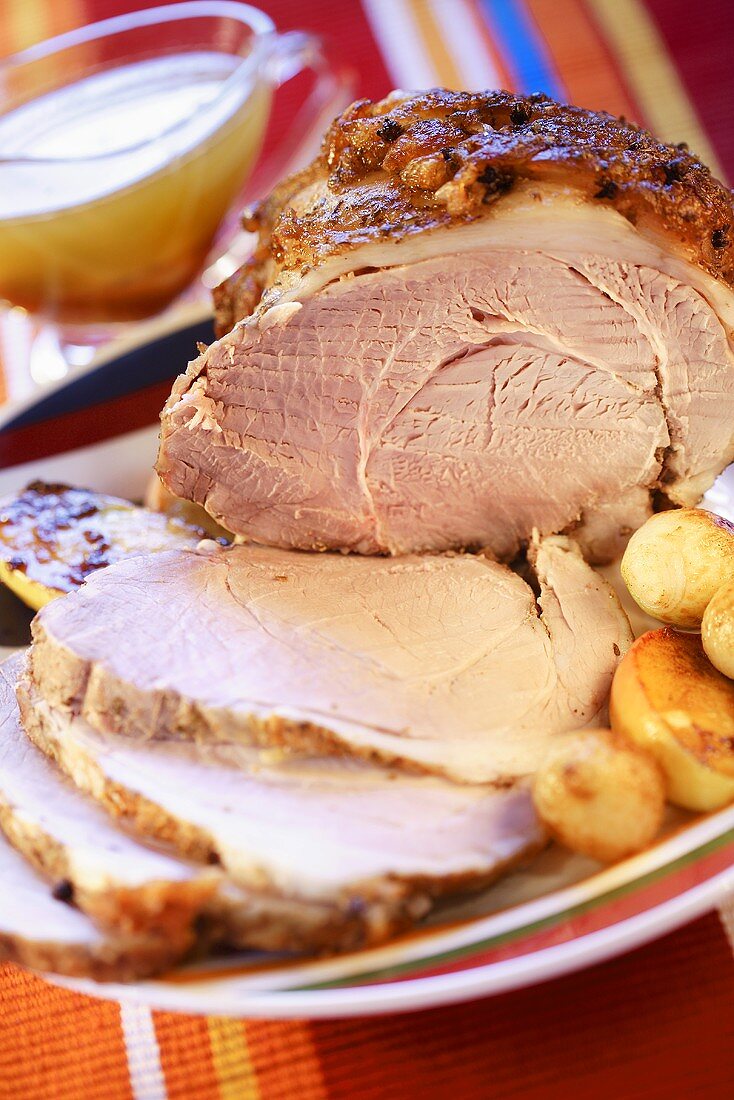 Roast pork with crackling, partly carved, with potatoes
