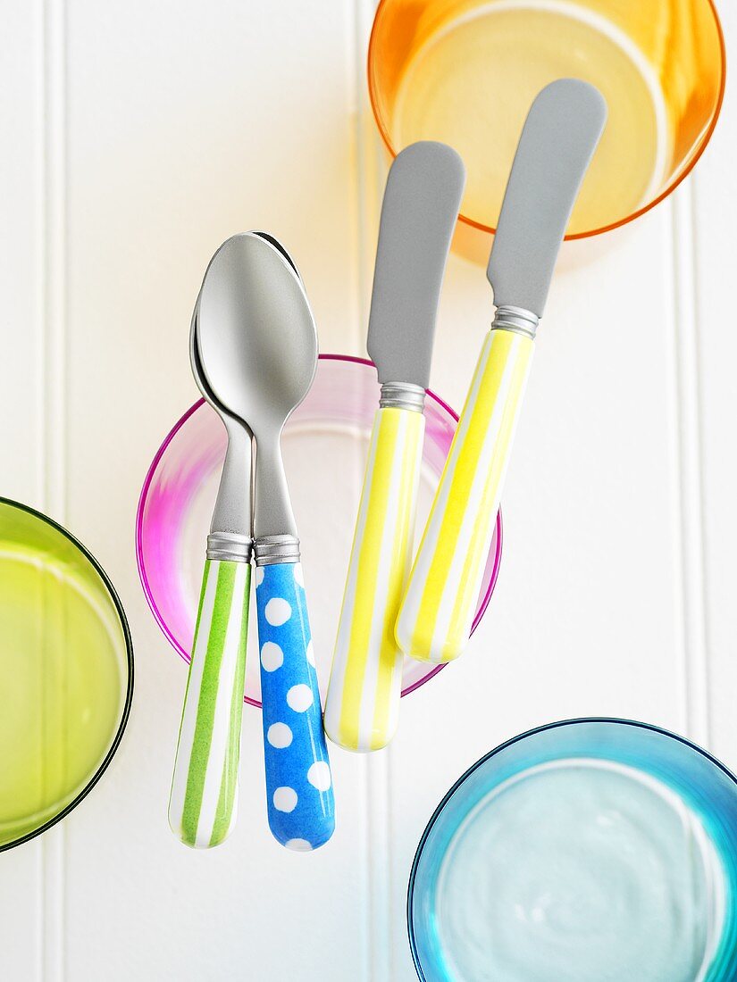 Coloured cutlery on coloured glasses
