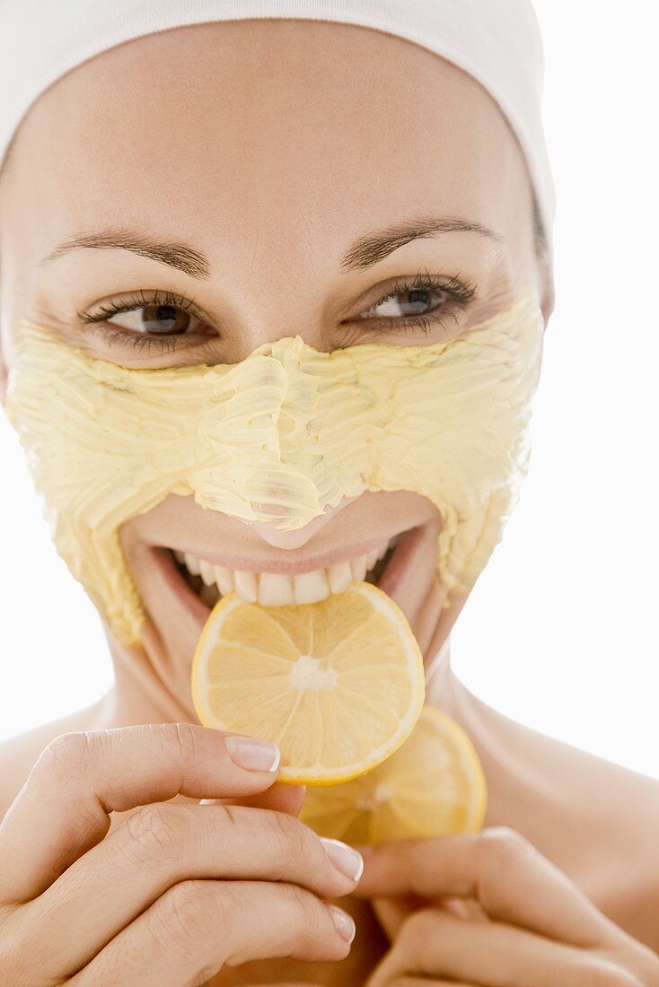 Frau mit Honig-Gesichtsmaske isst Zitrone