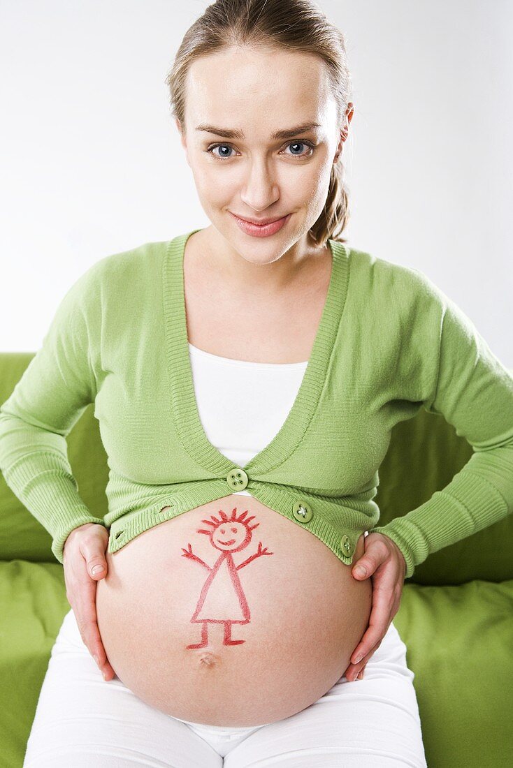Schwangere Frau mit aufgemalter Puppe auf dem Bauch