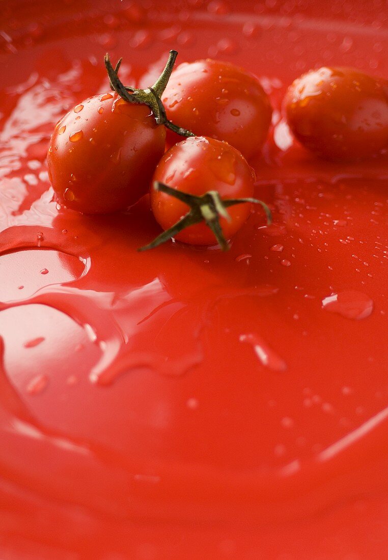 Kirschtomaten auf rotem Untergrund mit Wassertropfen