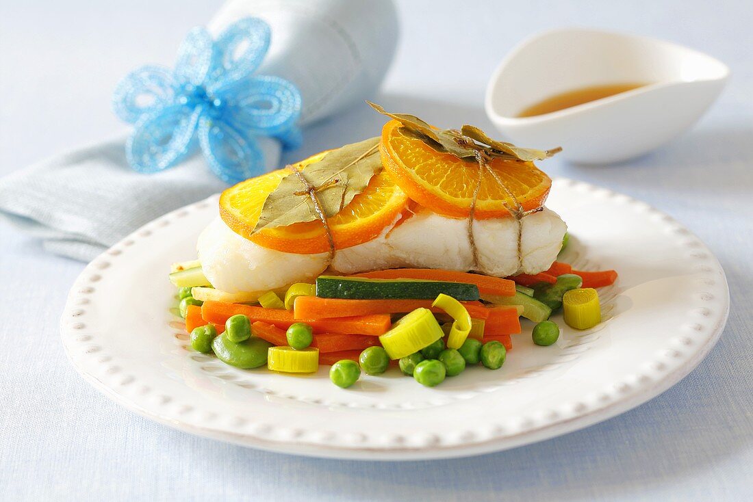 Baked halibut with orange slices on vegetables
