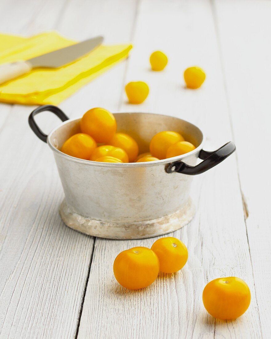 Yellow tomatoes in and beside pan