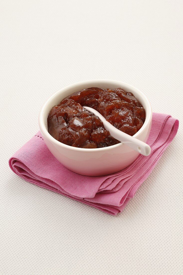 A small bowl of strawberry jam with a spoon