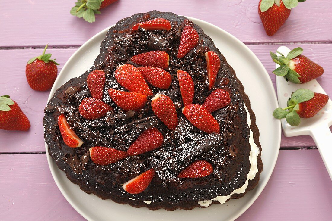 Schokoladenkuchen mit Schlagsahne und Erdbeeren in Herzform
