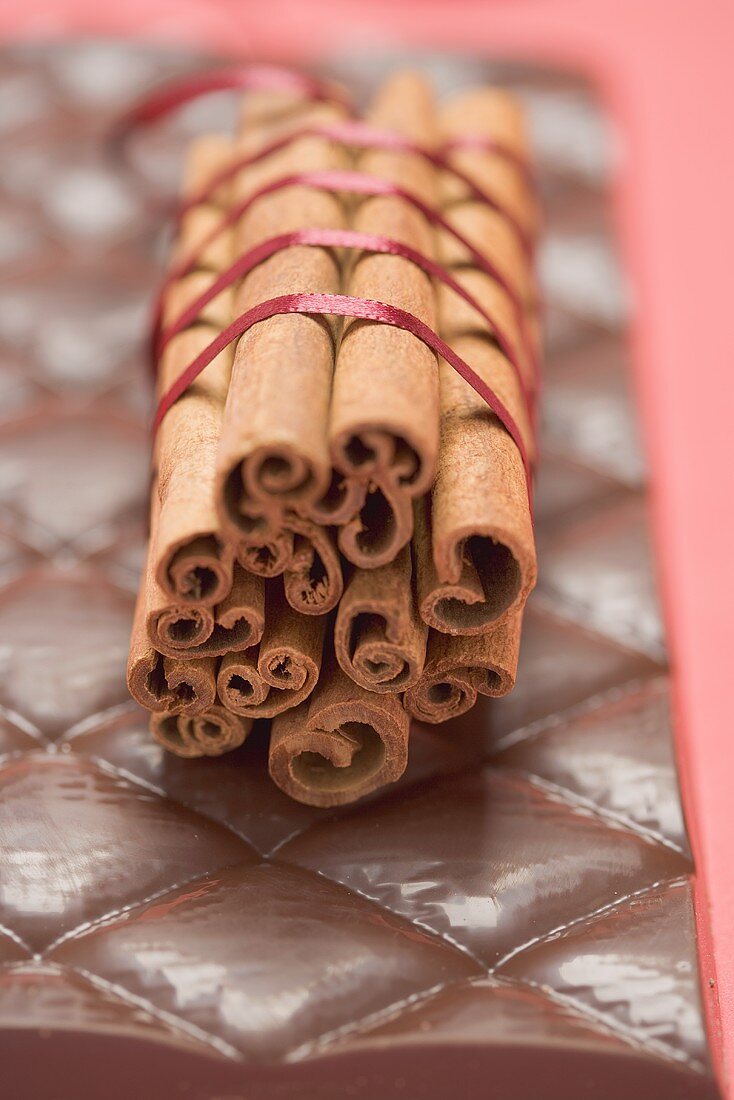 Cinnamon sticks, tied together with red ribbon, on chocolate