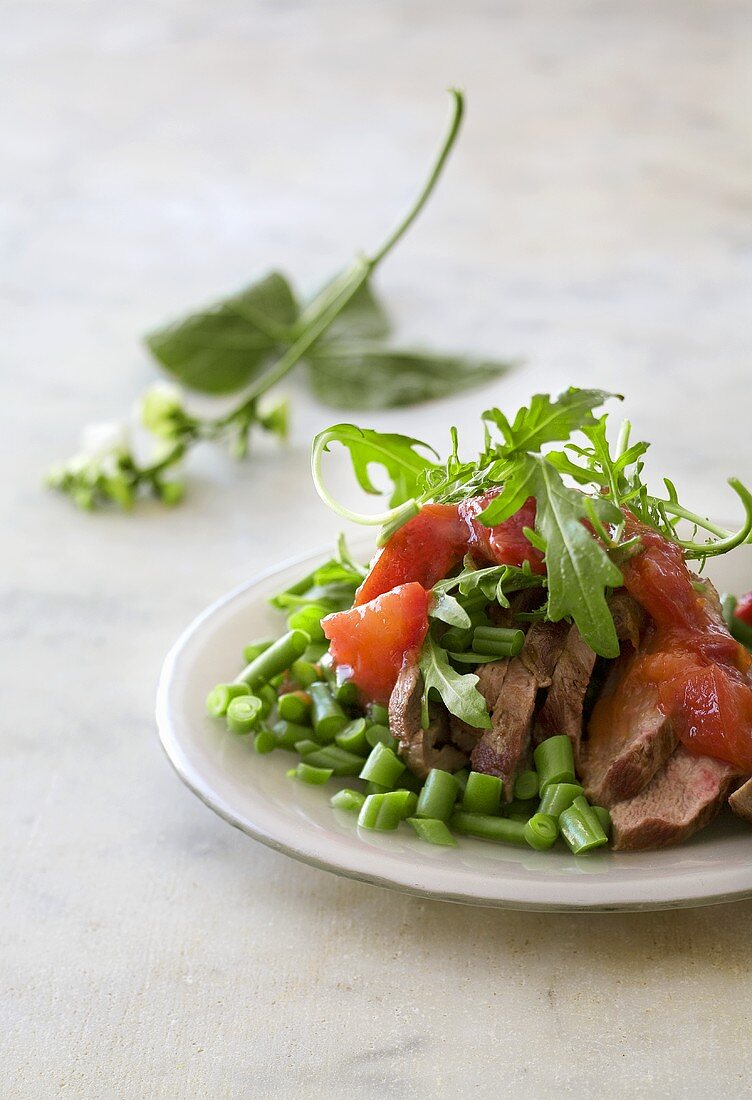 Beef medallions on bean salad with tomatoes and rocket