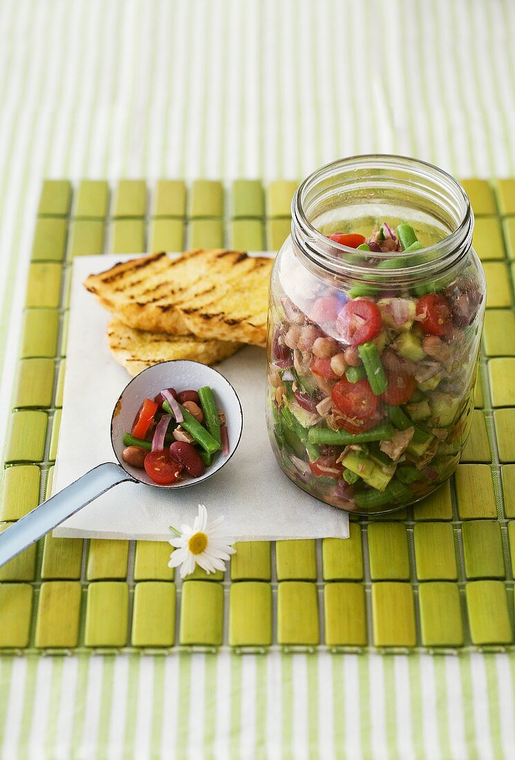 Bean, onion, cucumber and tomato salad in jar and ladle