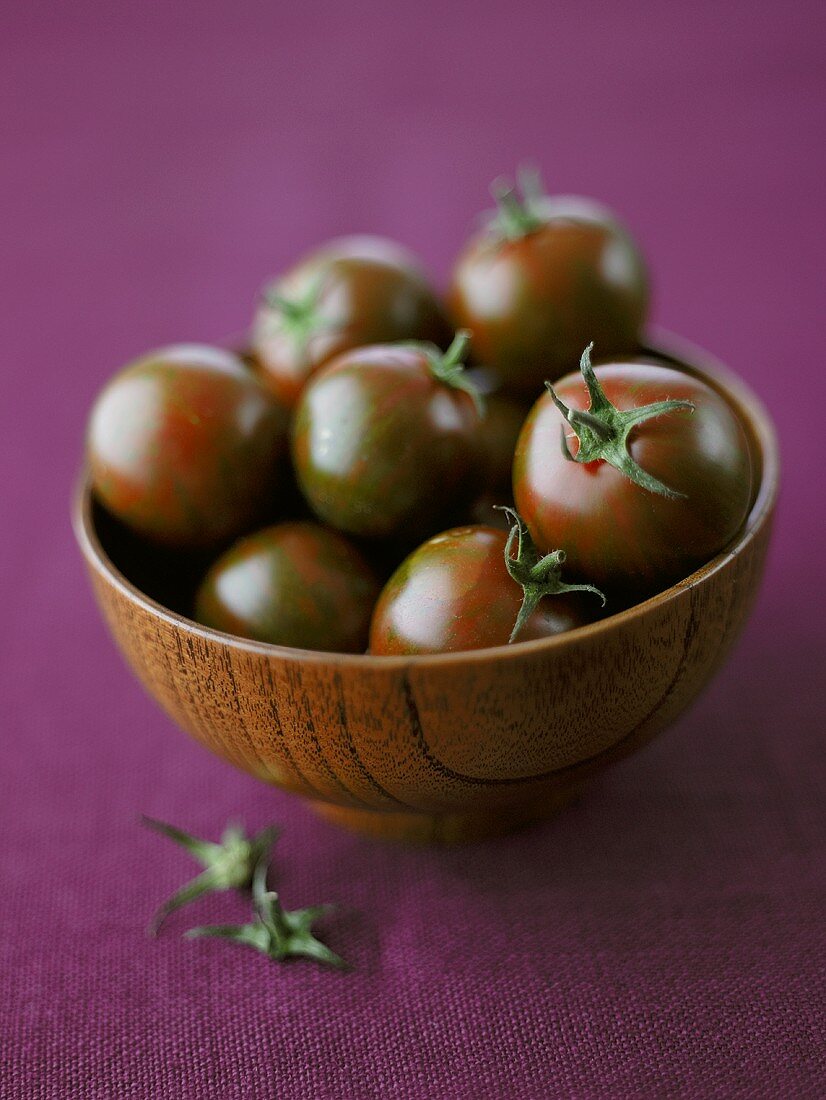 Schwarze Tomaten in einer Holzschüssel