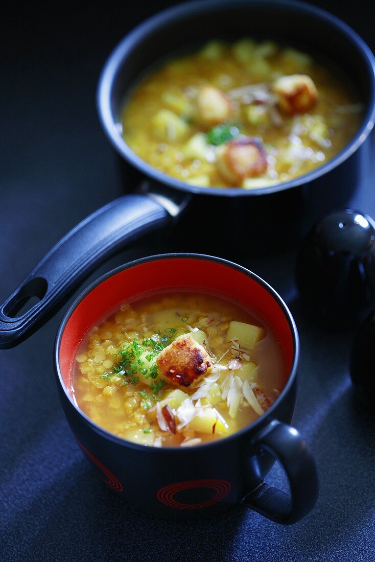 Linsen-Kartoffelsuppe im Topf und einer Tasse